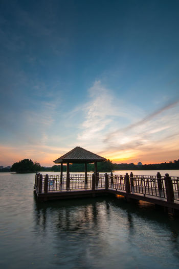 Jetty in lake against sky during sunset