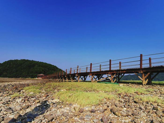 Bridge over land against clear blue sky