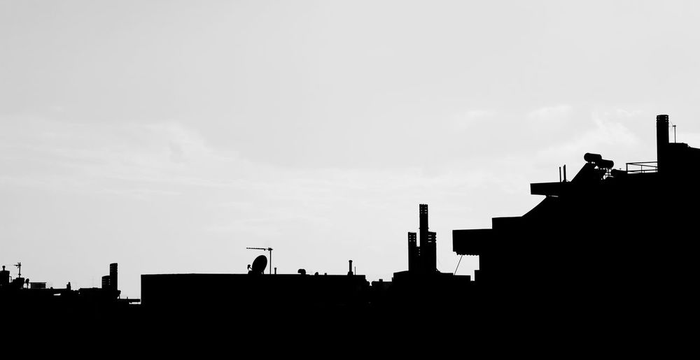 High section of silhouette buildings against sky