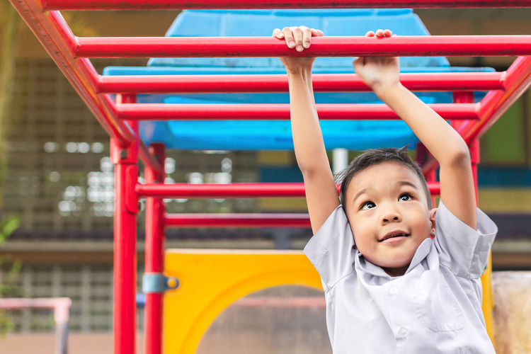 Boy hanging on parallel bars at playground
