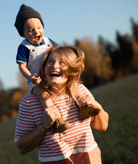 Happy mother carrying son on shoulders while standing in park