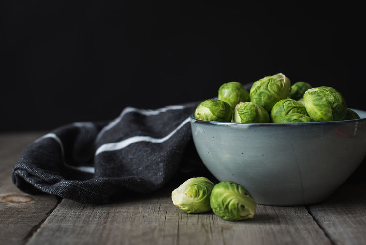 Bowl of brussels sprouts and napkin on a rustic wooden table.