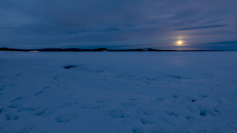 Scenic view of frozen lake against sky at dusk