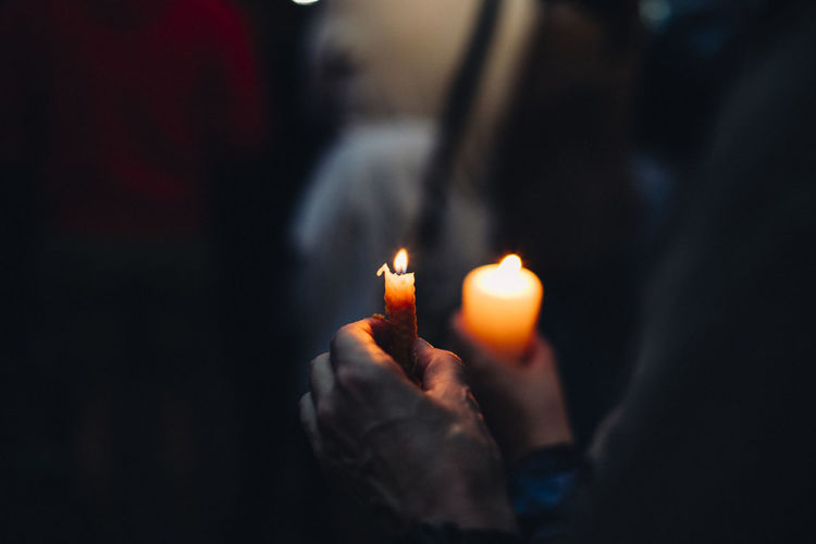 Close-up of hand holding lit candles
