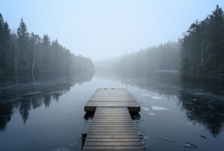 Pier over lake against sky during foggy weather