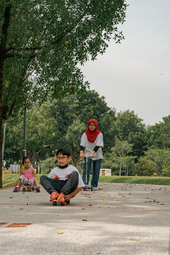 Children riding skateboard and scooter in the park.