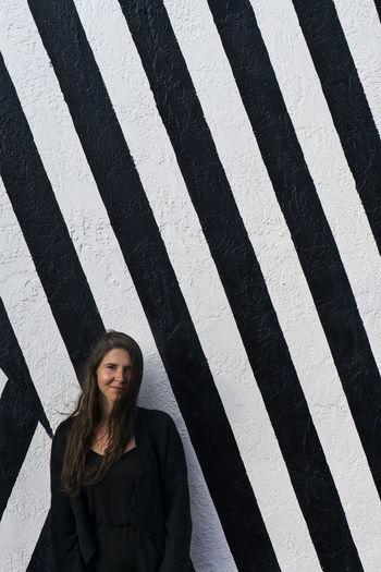 Portrait of woman standing against striped wall
