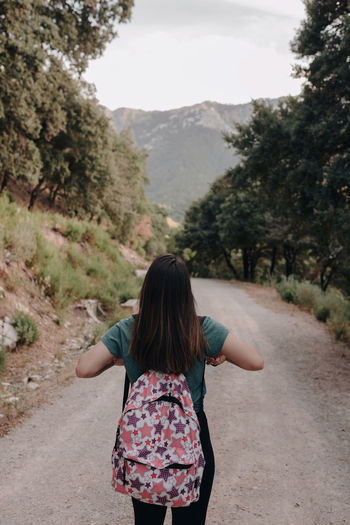 Rear view of woman standing on road against mountain