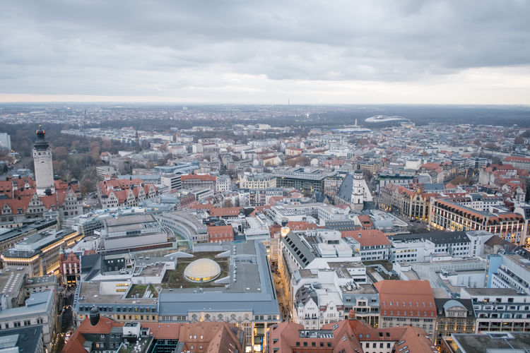 High angle view of city buildings against cloudy sky