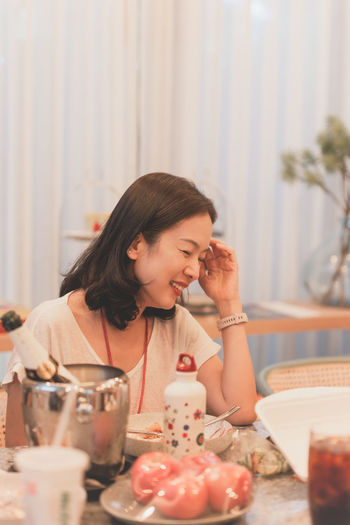 Happy woman looking away while sitting on table