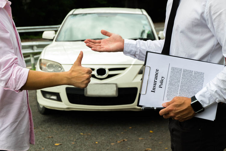 Cropped image of car insurance agent explaining policy to client gesturing thumbs up