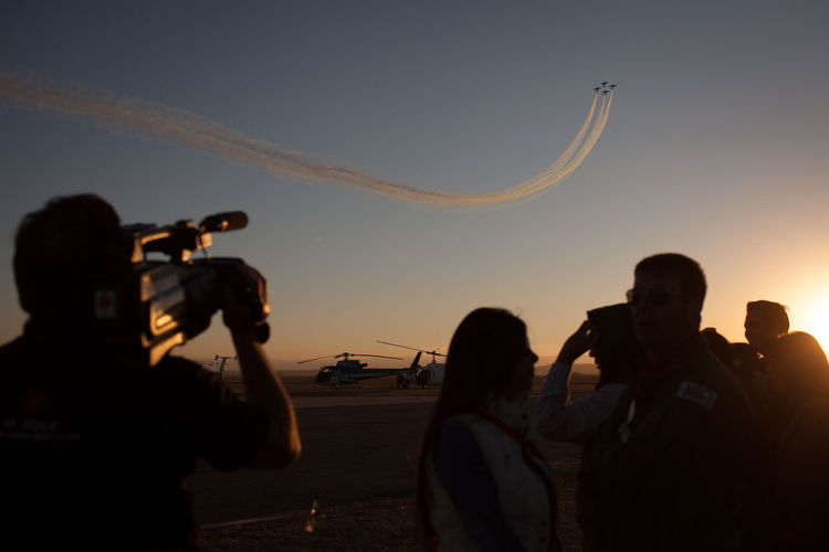 Rear view of man photographing airshow during sunset