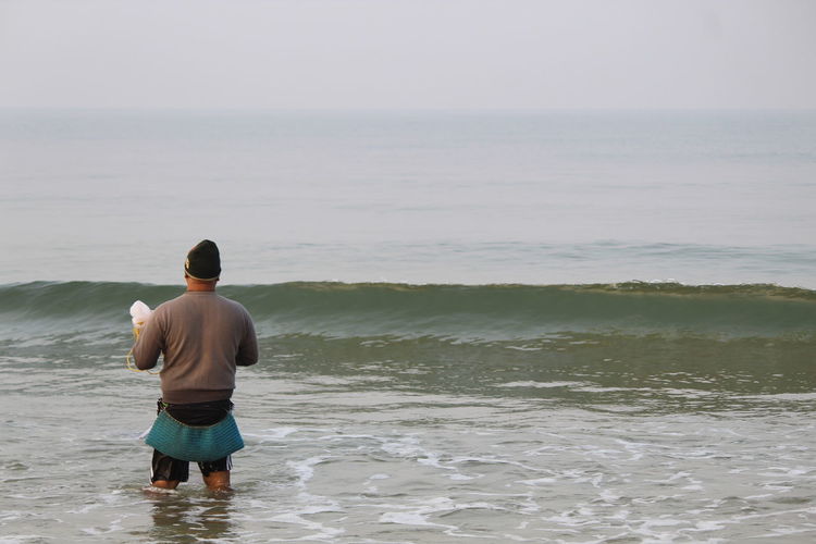 Rear view of man wading in sea