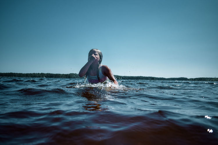 Young woman swimming in sea against clear sky