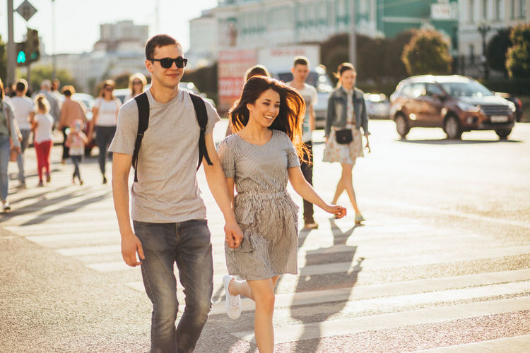 Smiling young couple walking on road in city