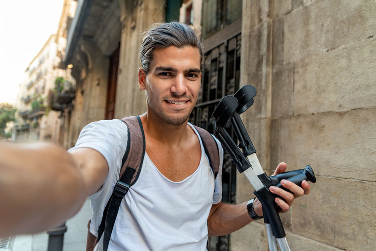 Selfie of young latin man with crutches in the street
