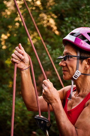 Active senior woman wearing prism glasses while holding climbing rope