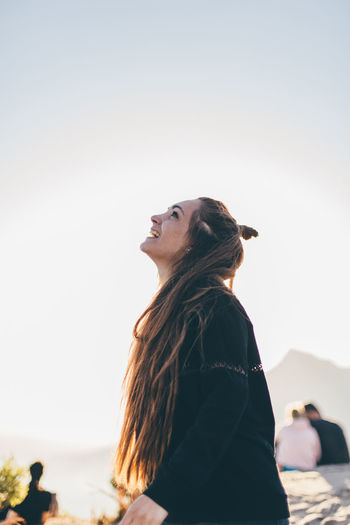 Smiling young woman standing against sky