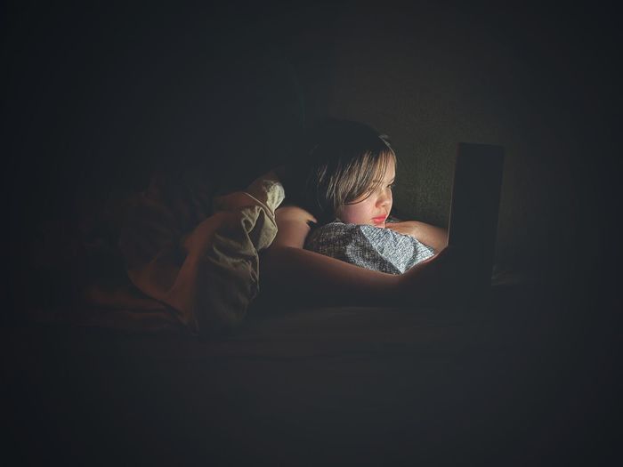 Ten-year-old girl using laptop in bed