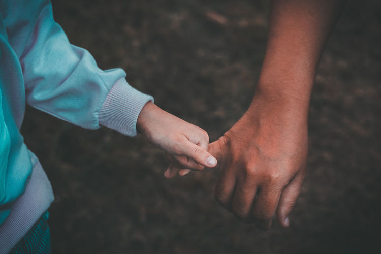 Cropped image of parent holding child hand on street