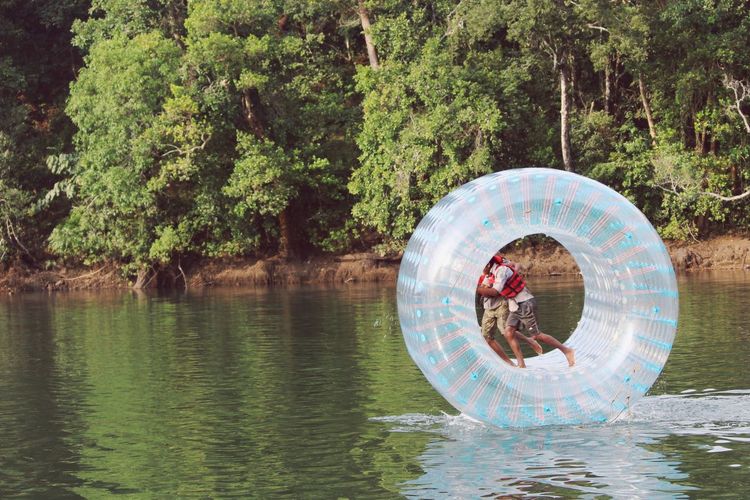 Side view of people on float ring against trees