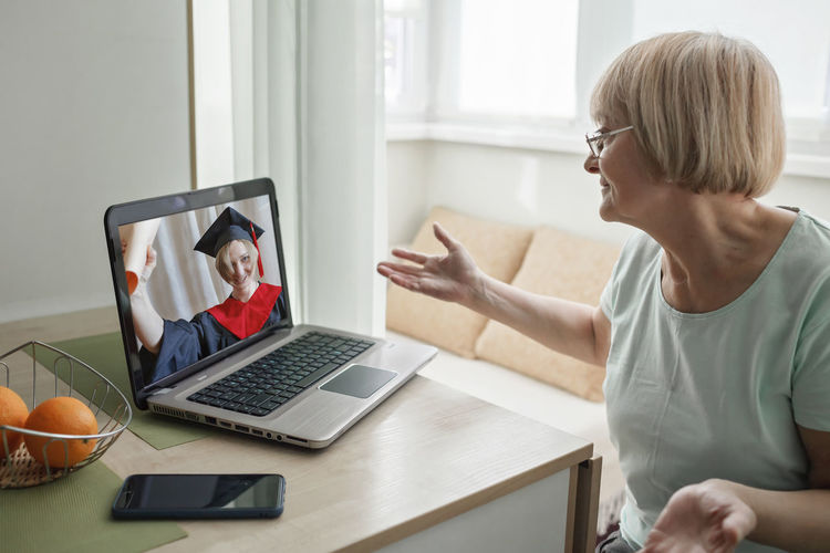 Woman gesturing while video conferencing over laptop on table