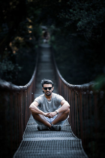Young man wearing sunglasses standing on footbridge