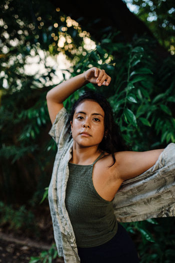 Latina girl with green shirt dancing surrounded by green leaves