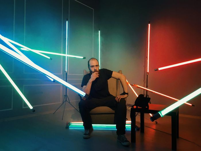 Portrait of man sitting in illuminated room