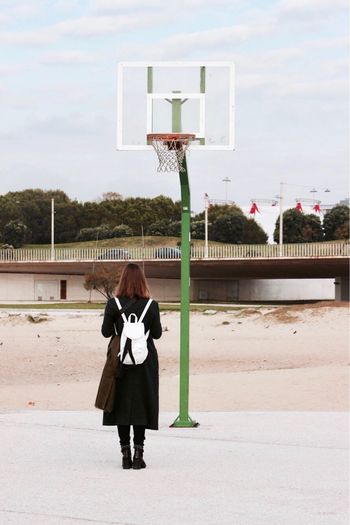 Rear view of woman standing against basketball hoop