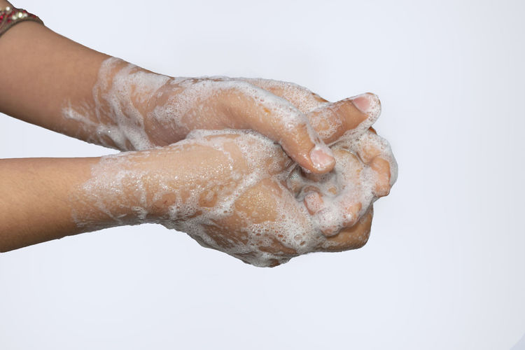 Close-up of hand holding water drops on white background