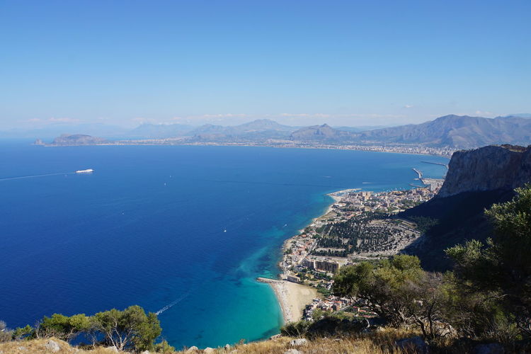 High angle view of sea and mountains against clear blue sky