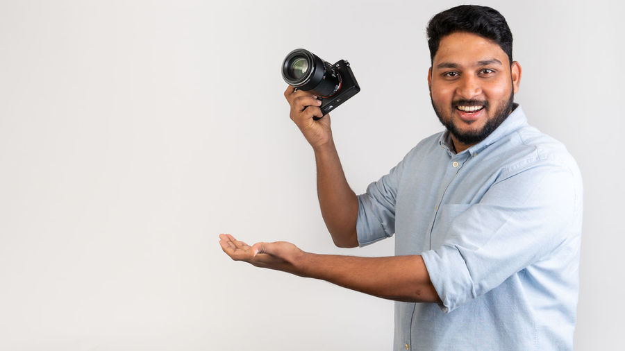 Portrait of man photographing against white background