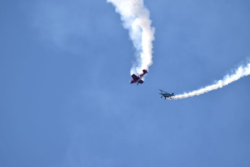 Low angle view of airshow against blue sky during sunny day