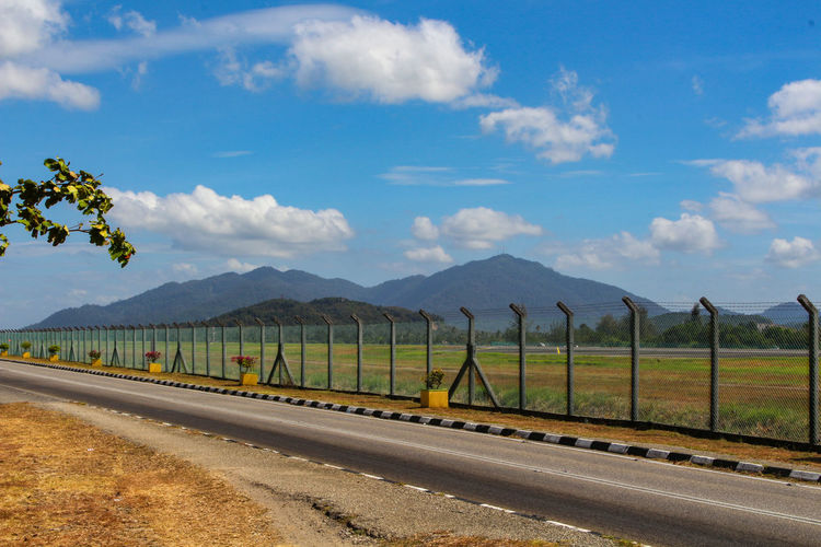 Road amidst field against sky