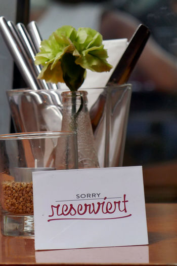 Reserved sign by flower in vase on table at restaurant
