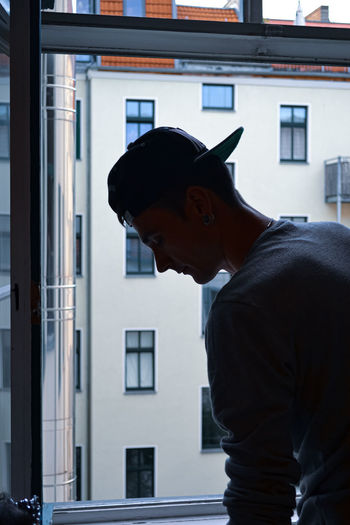 Side view of young man looking through window
