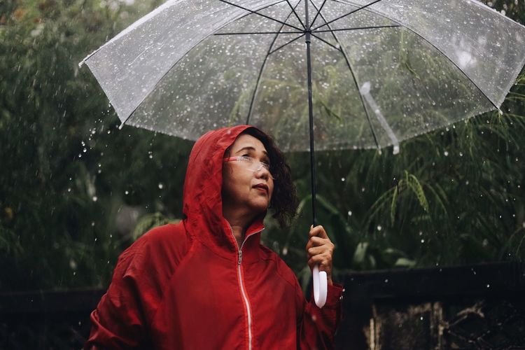 Young woman looking through wet window during rainy season