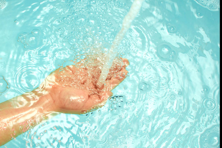 Close-up of hand on wet swimming pool