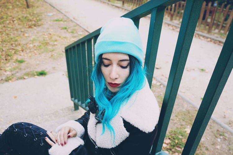 High angle view of young woman with blue hair sitting on steps