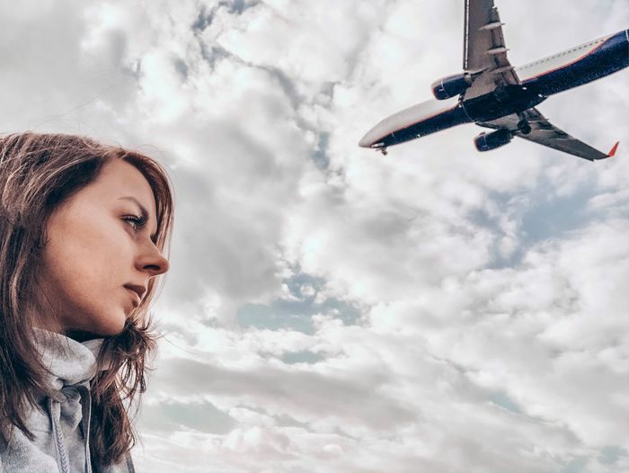 Low angle portrait of woman looking away against sky