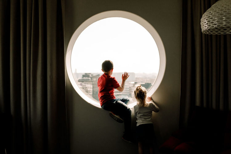 Siblings by window in hotel room