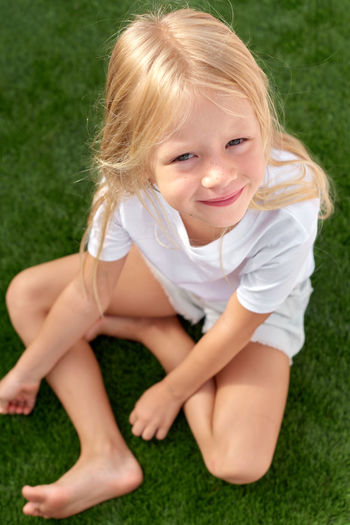 Portrait of cute girl sitting on grassy field
