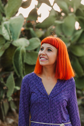 Close-up of smiling woman standing against plants