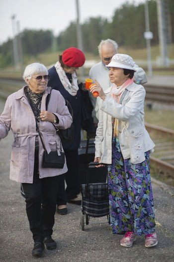 Positive elderly seniors people waiting train before traveling during a pandemic