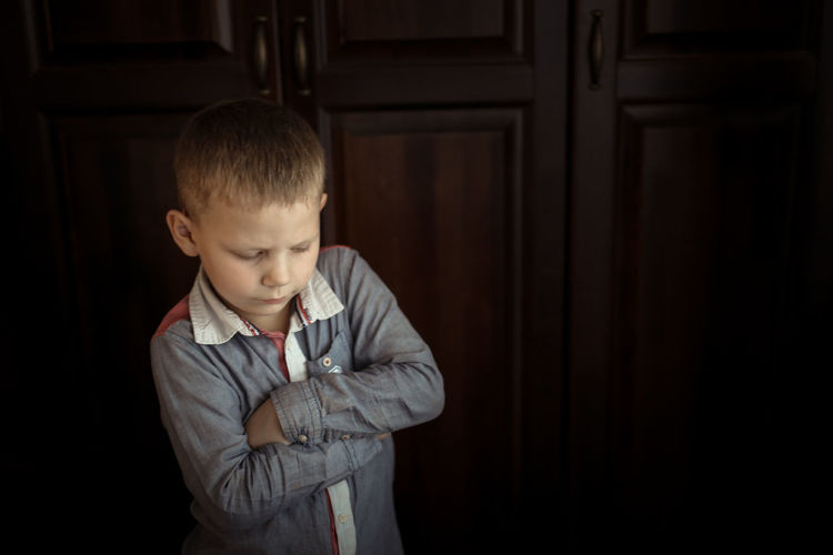 Portrait of boy looking away while standing at home