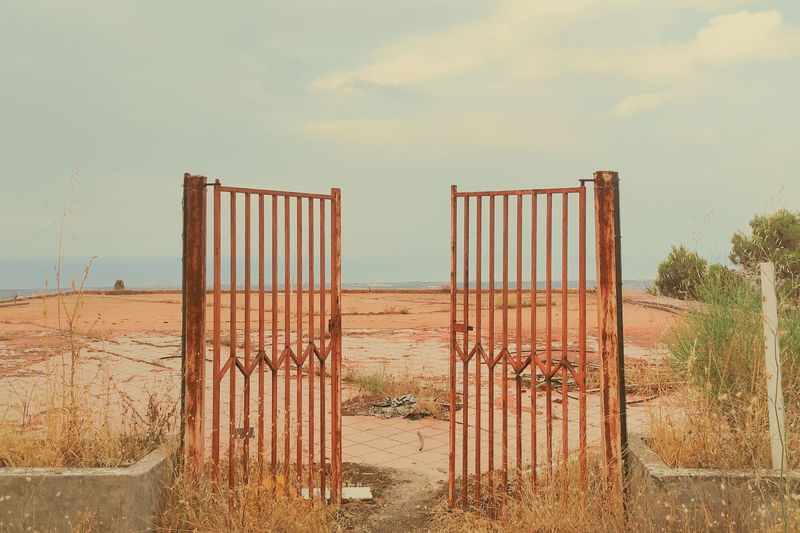 Wooden gate on beach against sky