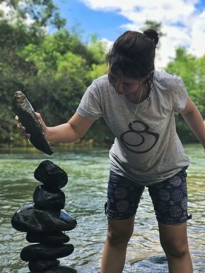 Woman stacking stones while standing in river