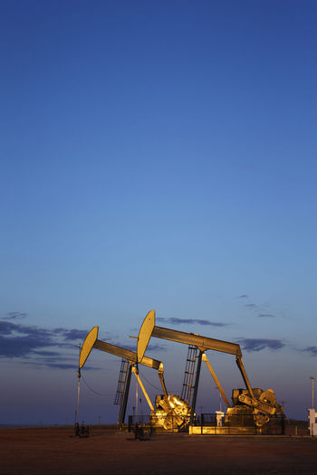 Oil pumps on field against blue sky during dusk