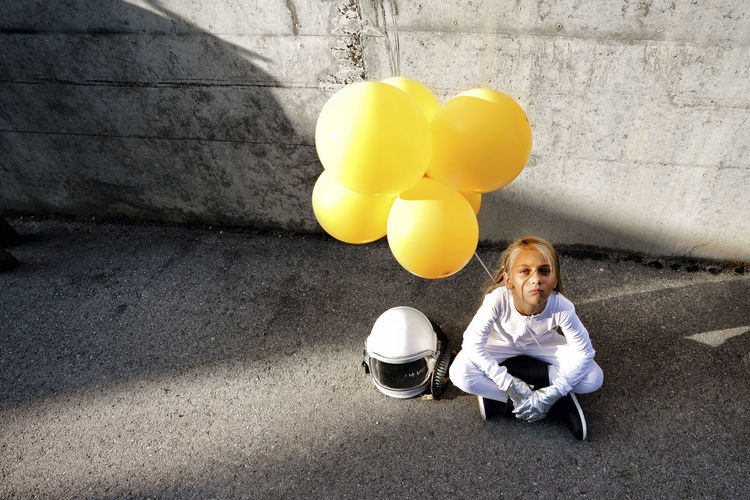 Portrait of a smiling woman sitting on balloon against wall